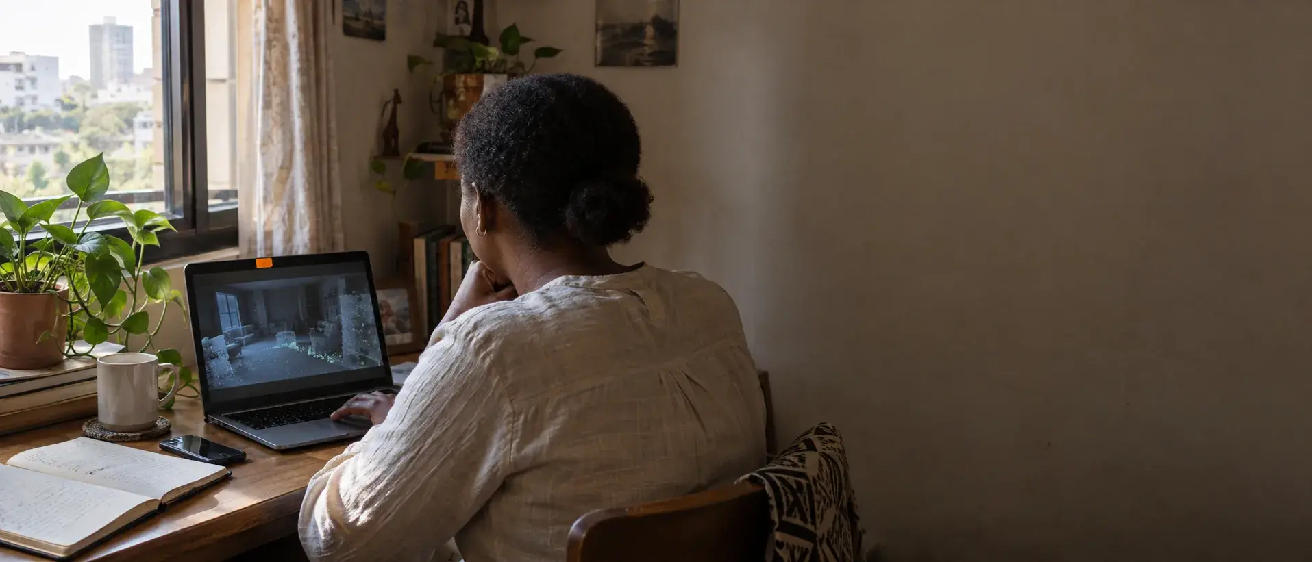 A person at a desk in natural light, reviewing multi-sensor robot footage on a laptop.